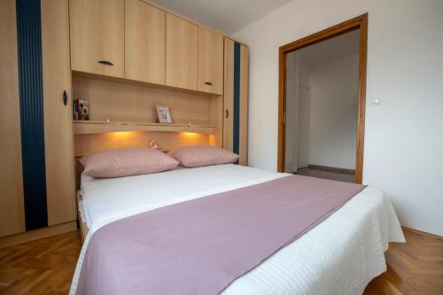 1 dormitorio con 1 cama blanca y 2 almohadas rosas en Apartment Anita, en Makarska