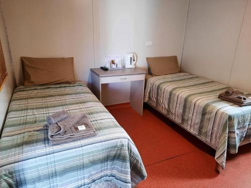a room with two beds and a table with a microwave at Boab Inn in Derby