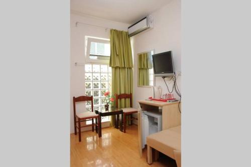 a living room with a desk and a bed and a television at BMV room for 2-3 persons in Sveti Stefan