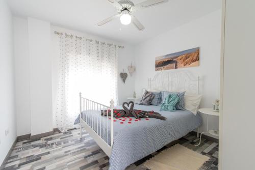 ein weißes Schlafzimmer mit einem weißen Bett und einem Deckenventilator in der Unterkunft Ajuy Paradise Beach in Ajuy