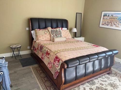 a bedroom with a large bed with a leather headboard at Chateau Couchebout in Pugnac
