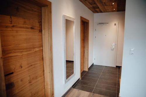 a hallway with a wooden door and a mirror at Zillertal Juwel in Fügen