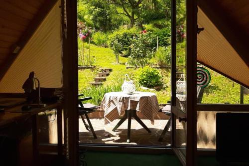 a room with a table and a view of a yard at Wooden cabin with a view in Idrija