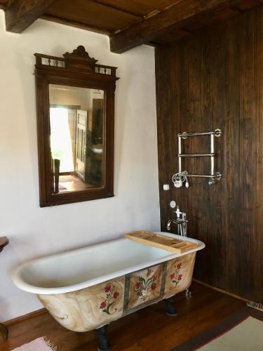 a large bath tub in a bathroom with a mirror at Count Kálnoky's Transylvanian Guesthouses in Micloşoara