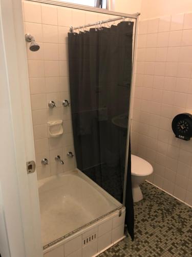 a bathroom with a shower with a tub and a toilet at Blue Gums Hotel Motel in Teatree Gully