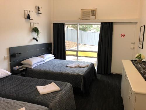 a hotel room with two beds and a window at Blue Gums Hotel Motel in Teatree Gully