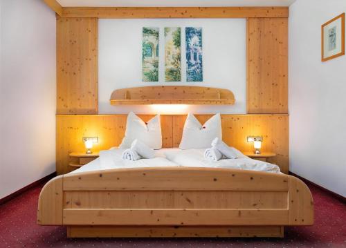 um quarto com uma grande cama de madeira com almofadas brancas em Gasthof Hotel Schermer em Bad Häring