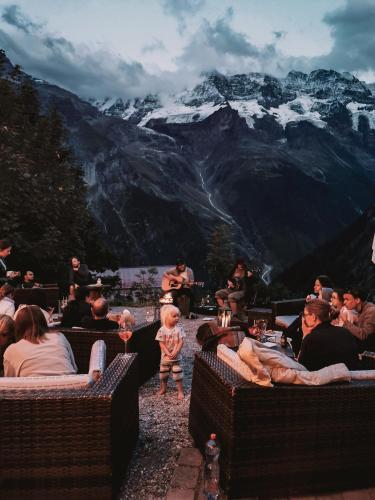 a group of people sitting at tables in front of a mountain at Mountain Hostel Gimmelwald in Gimmelwald