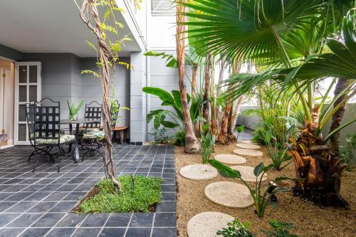 a courtyard with palm trees and a table and chairs at Romney Park Luxury Apartments by The Stay Collection in Cape Town