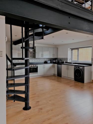 a large kitchen with a spiral staircase in a loft at The Studio in Farmborough