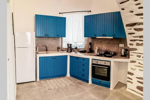 a kitchen with blue cabinets and a white refrigerator at Kostos House BLUE in Kóstos