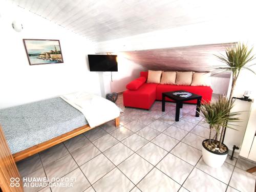 a living room with a red couch and a bed at Albert Apartaments Krk in Krk