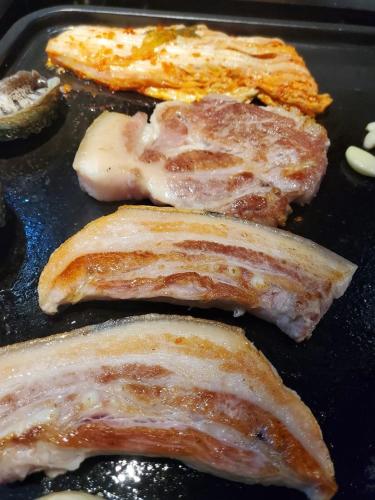 four pieces of meat cooking on a pan at The Stay Century Hotel in Jeju