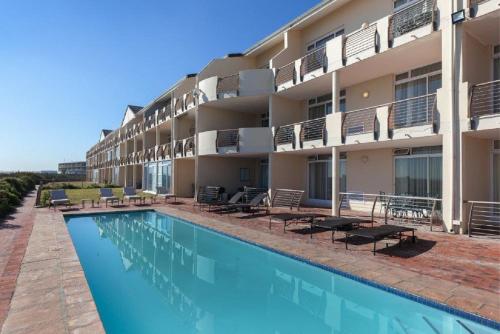 a hotel with a swimming pool in front of a building at Cape Town Beachfront Apartments at Leisure Bay in Cape Town