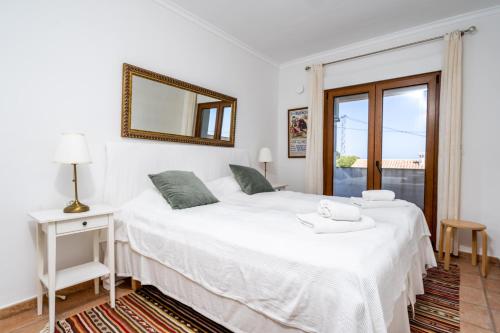 ein Schlafzimmer mit einem großen weißen Bett und einem Spiegel in der Unterkunft Casa Ann in Denia