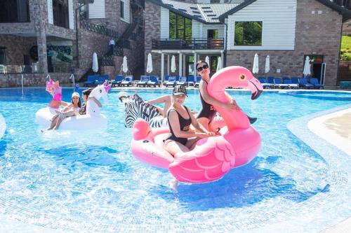 een groep mensen die op flamingo's rijden in een zwembad bij Westhills Cottage Town & Spa in Boekovel