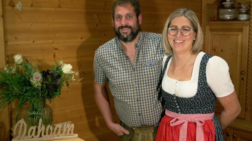 a man and a woman standing next to a table with flowers at Pension Traube in Uderns