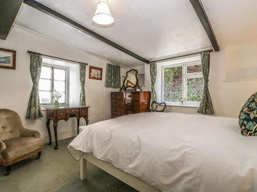 a bedroom with a bed and a desk and windows at Small Piece in Minehead