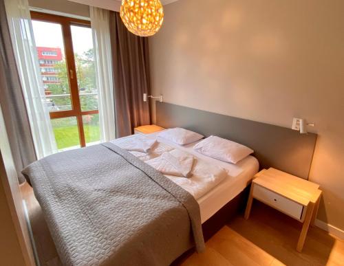 a bed in a room with a large window at Apartamenty Bałtyckie - Wczasowa - osiedle zamknięte, winda, miejsce parkingowe in Ustka