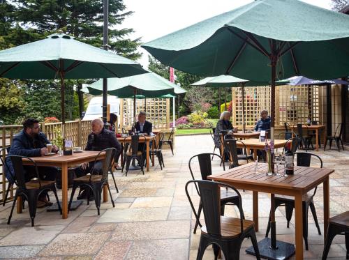 a group of people sitting at tables with umbrellas at Woodlands Hotel, BW Signature Collection in Dundee