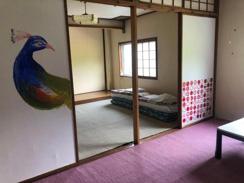 Guest House Shiroikiseki في توياما: غرفة مع مرآة مع لوحة طاووس على الحائط