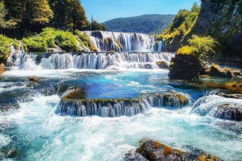 un gruppo di cascate su un fiume con rocce di Villa Behić a Bihać