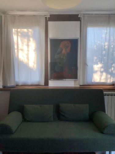 a green couch in a living room with two windows at Tavern di Arqua' in Arqua Petrarca