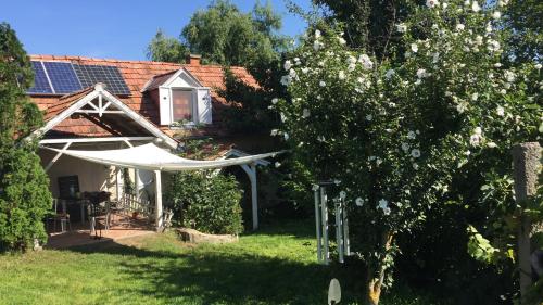 une maison avec un jardin et un arbre avec des fleurs blanches dans l'établissement Csobánc Szerelem-Nemzeti Park-Önalló Ház, à Gyulakeszi