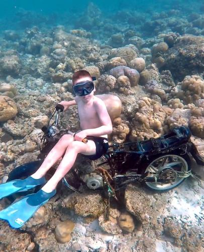 a man sitting on a motorcycle in the water at Sabba Beach Suite , Fodhdhoo - Maldives in Velidhoo