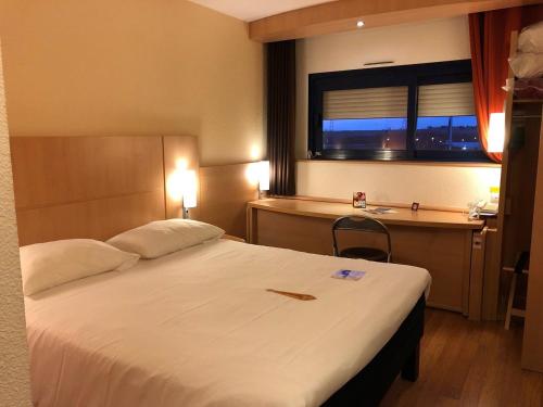 a bedroom with a large white bed with a window at ibis Site du Futuroscope in Chasseneuil-du-Poitou