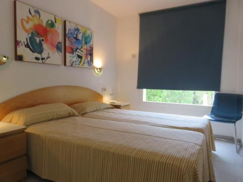 - une chambre avec un lit doté d'une chaise bleue et d'une fenêtre dans l'établissement Apartamentos Mar D'Or, à L'Estartit
