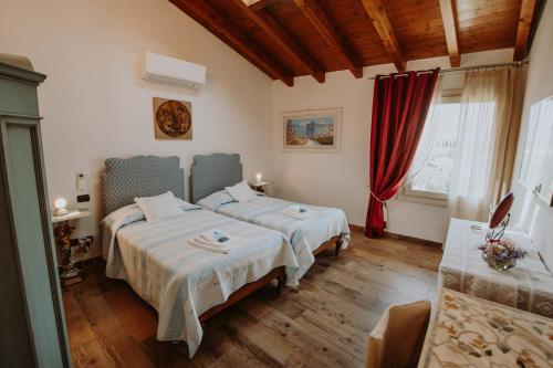 sypialnia z 2 łóżkami i czerwoną zasłoną w obiekcie B&B Casa Santa Lucia w Manerba del Garda