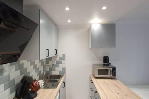 une cuisine avec des armoires blanches, un évier et un micro-ondes dans l'établissement Rambouillet, Studio, proche gare et chateau, à Rambouillet