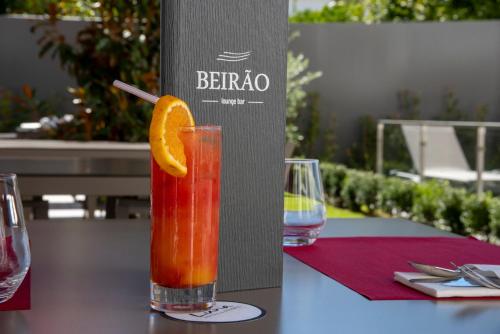 a drink with an orange slice on a table at Luna Hotel de Tábua in Tábua