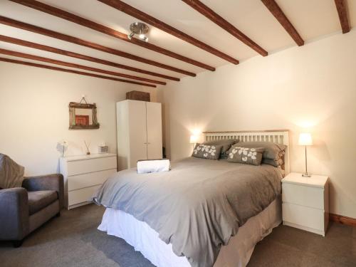 a bedroom with a large bed and a chair at Chestnuts Barn in Belper