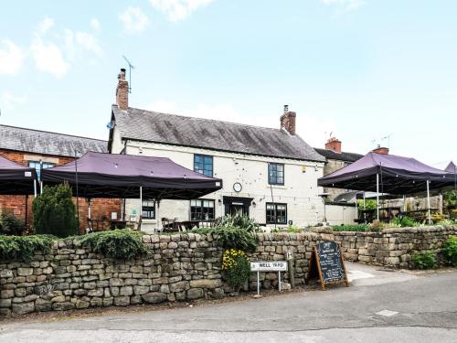 a building with purple umbrellas next to a stone wall at Chestnuts Barn in Belper