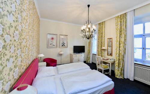 a hotel room with two beds and a desk at Hotel Bischofshof am Dom in Regensburg