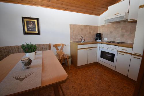 cocina con armarios blancos y mesa de madera en Landhaus Bichlbach, en Bichlbach