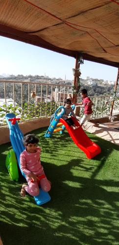two young children playing on an outdoor playground at Al Misfah Hospitality Inn in Misfāh