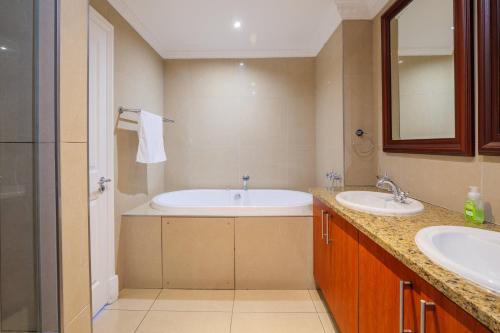 a bathroom with two sinks and a bath tub at The Sails G6-07 on Timeball Boulevard in Durban