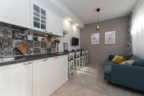 a kitchen with white cabinets and a blue couch at Pansion Tina in Šilo
