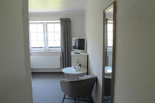 a room with a mirror and a table and a chair at Hotel-Pension Am Fuchsberg in Bad Doberan