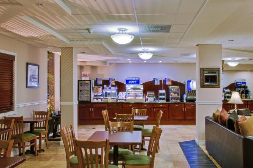 a restaurant with tables and chairs and a bar at Holiday Inn Express West Palm Beach Metrocentre by IHG in West Palm Beach