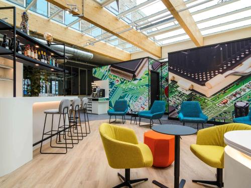 a bar with colorful chairs and a mural at ibis Styles Delft City Centre in Delft