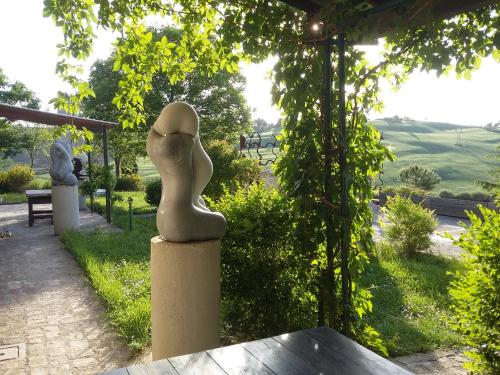 a statue of a woman sitting on a column in a garden at "La Casa degli ulivi Art B&B" in Trecastelli