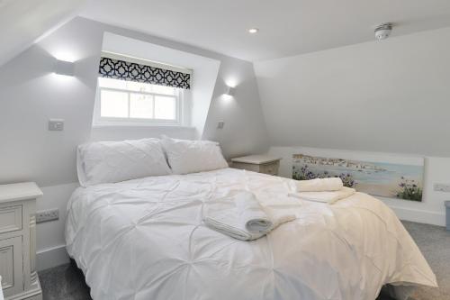 a white bedroom with a large white bed with a window at Master accommodation suite 4 attic room in Hastings