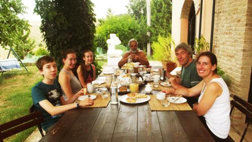a group of people sitting around a wooden table at "La Casa degli ulivi Art B&B" in Trecastelli