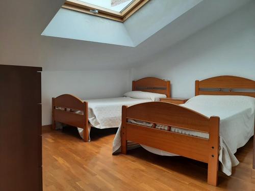 a bedroom with two beds and a skylight at Ático La Plaza in Arriondas
