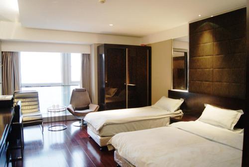 a hotel room with two beds and a chair at Nanjing Kaibin Apartment -Xin Jie Kou in Nanjing