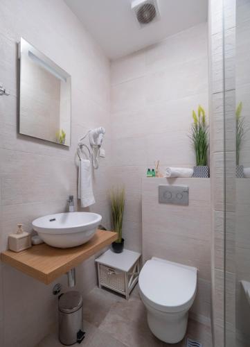 a white bathroom with a sink and a toilet at Apartments Garden Azure Budva in Budva
